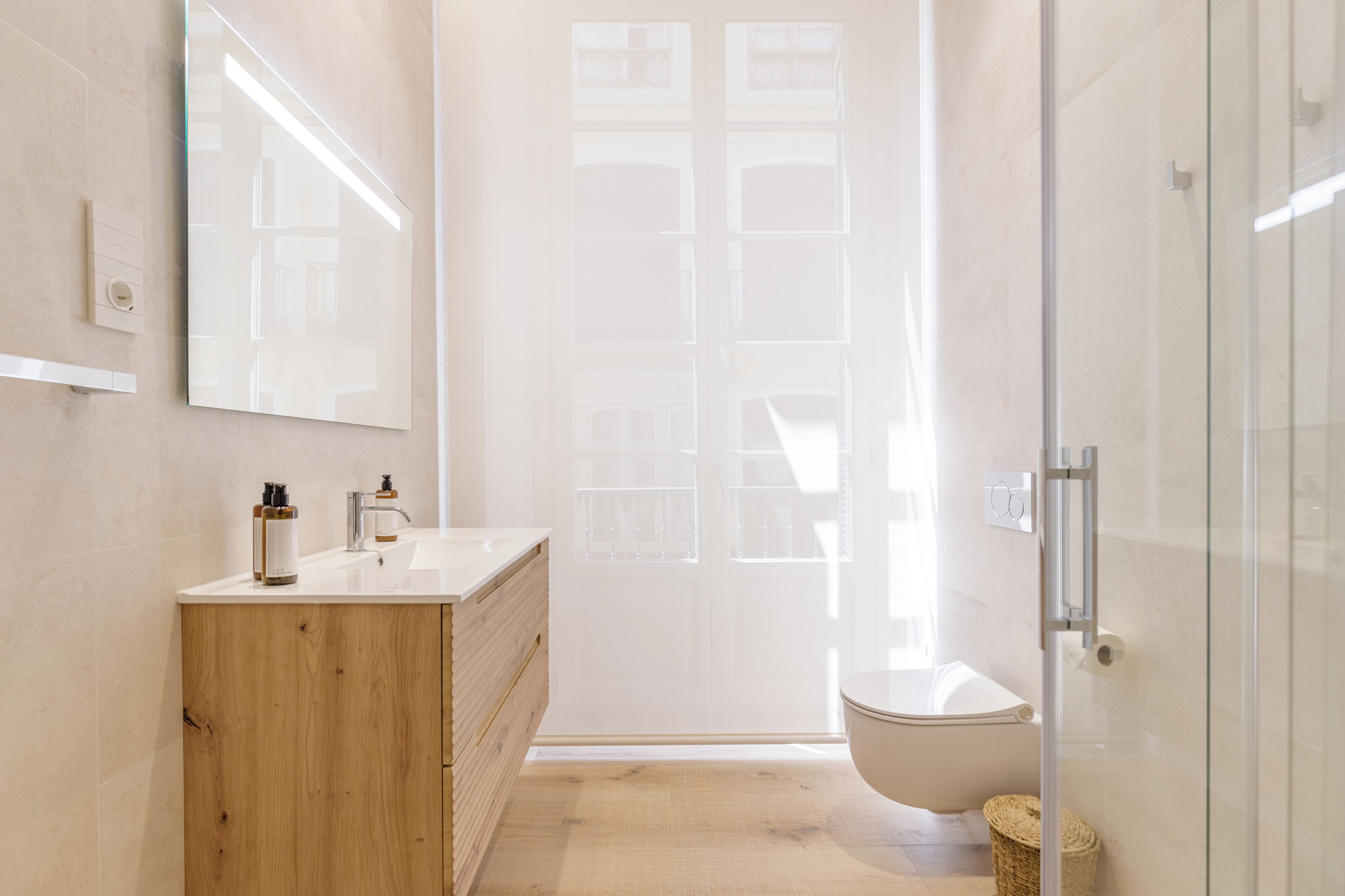 Un bagno moderno con un mobile vanitario in legno, un ampio specchio, cabina doccia in vetro e una vasca da bagno bianca.