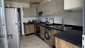 A modern kitchen with a built-in washer, stainless steel appliances, and a black countertop. - Agadir Bay, a comfy apartment with pool (Agadir)