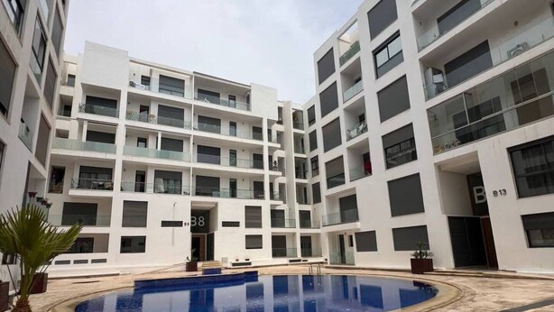 A modern multi-story residential building with a central courtyard featuring a swimming pool. - Agadir Bay, a comfy apartment with pool (Agadir)