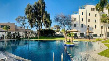 Una piscina al aire libre, sombrillas, sillones reclinables de piscina