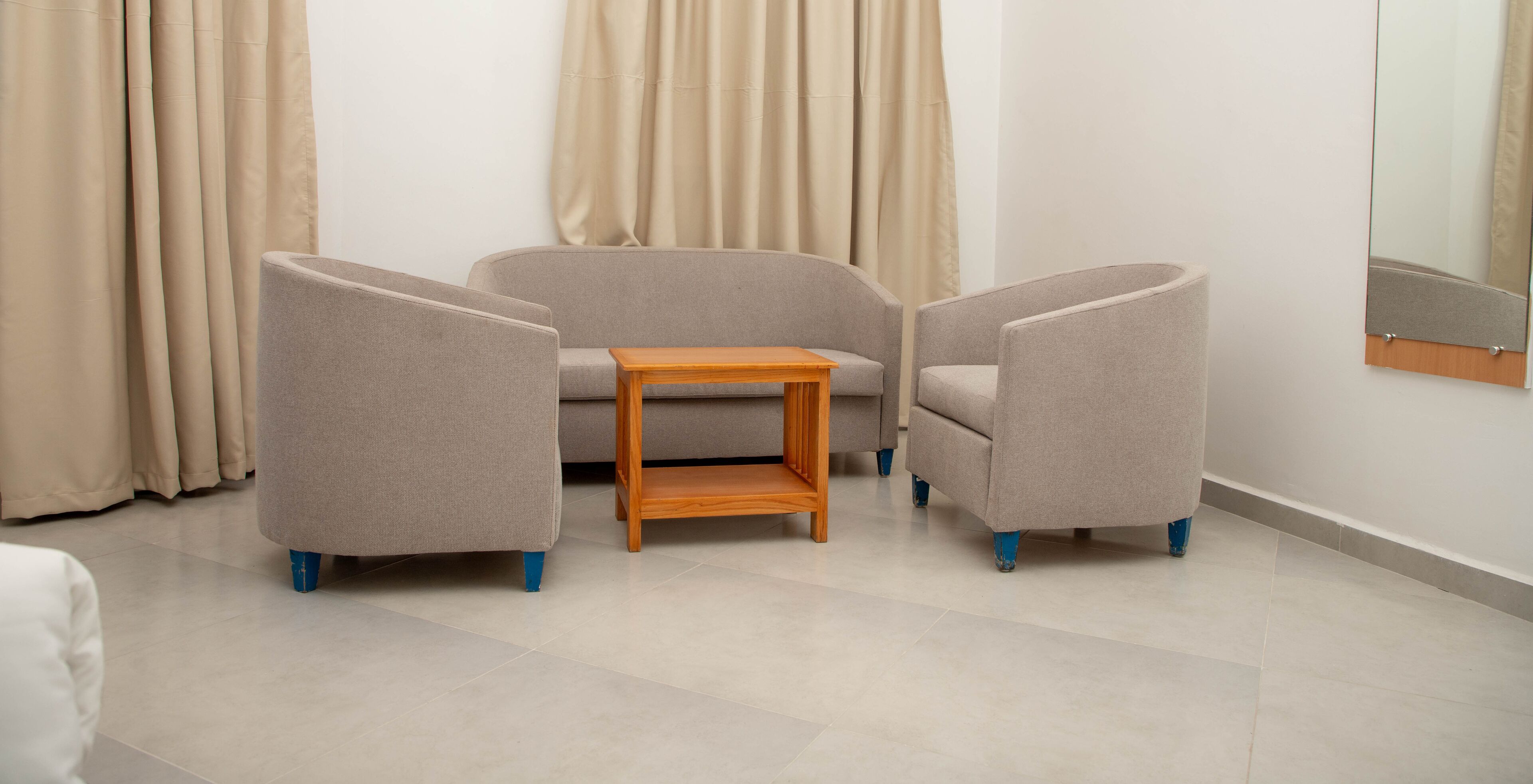 Een moderne woonkamer met een bank, twee fauteuils en een kleine houten tafel.