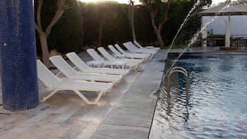 Zona de piscina amb gandules blanques i una columna emblada de blau.