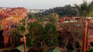 A residential area with terraced houses, a view of the sea, and a well-maintained garden with palm trees and hexagonal planters. - La Reserva de Marbella Penthouse  (Marbella)