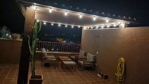 A rooftop terrace with string lights, seating, and a cactus plant. - La Reserva de Marbella Penthouse  (Marbella)