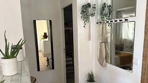 Un passadís amb terra de rajola, una banca, un mirall i plantes en testos.
