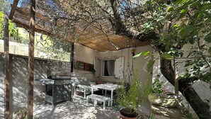 Terrassa exterior coberta amb una barbacoa, seients i plantes en testos.
