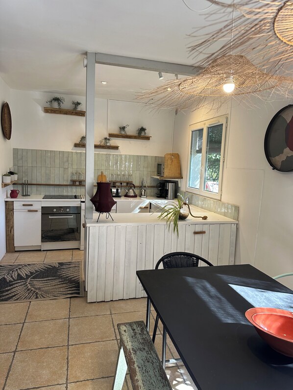 A modern kitchen with white cabinetry, a central island, and a dining area with a black table.