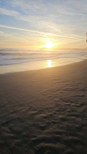 A beach with a sunset over the ocean.
