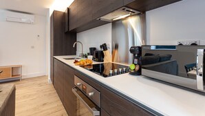 Una cucina moderna con piano cottura integrato, lavello e forno a microonde. Si nota un mobiletto in legno e una cappa aspirante in acciaio inossidabile.