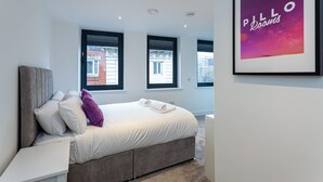 Una camera da letto moderna con un letto grande, una testiera e un'opera d'arte incorniciata al muro.