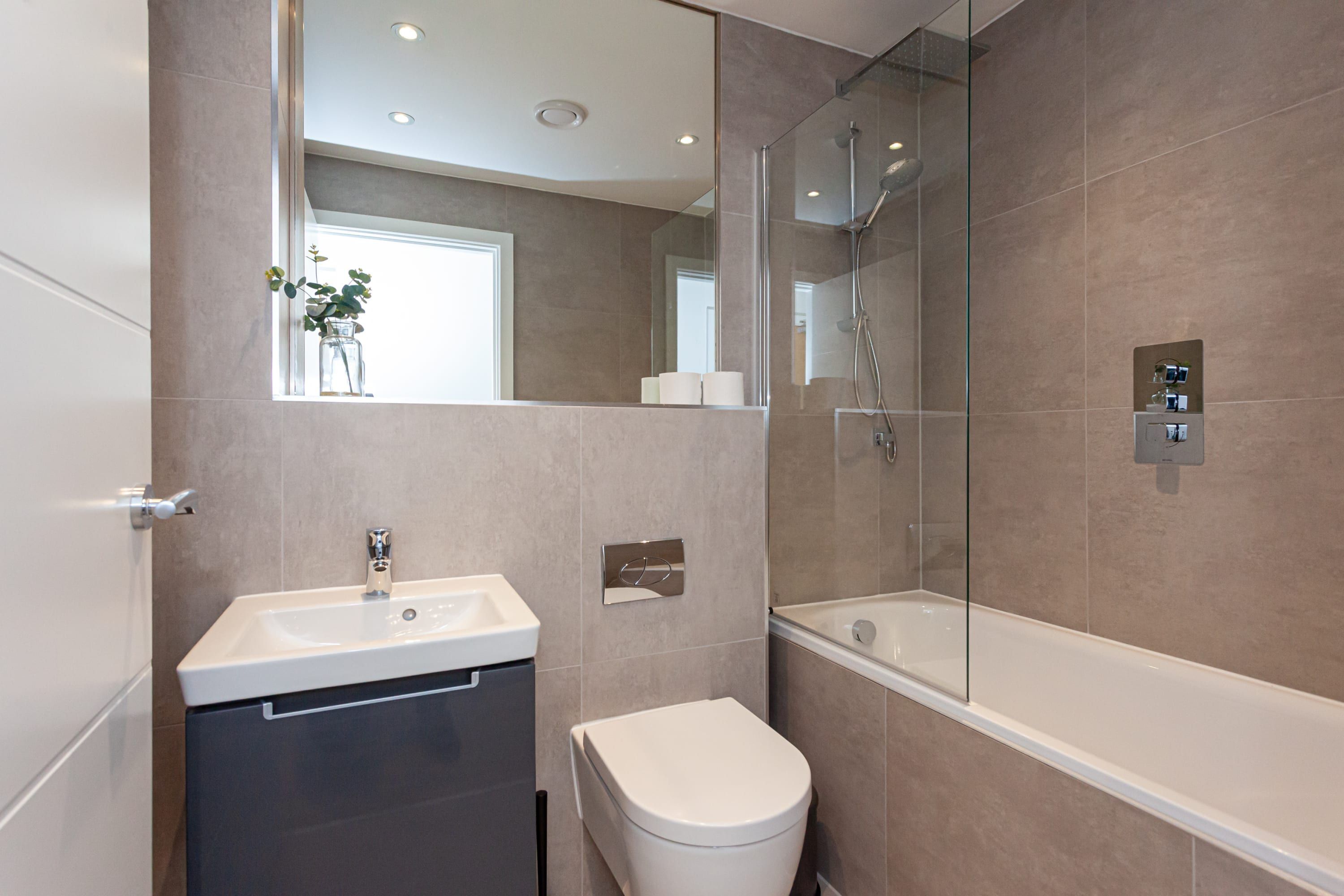 A modern bathroom with a sink, toilet, and bathtub.