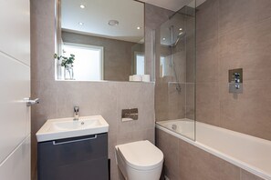 Un baño moderno con lavamanos, inodoro y bañera.