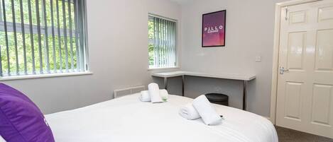 A hotel room with a large bed, a fireplace, a window with blinds, and a door.