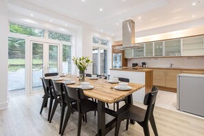 Een moderne keuken met een houten eettafel, een inbouwoven en een roestvrijstalen afzuigkap.