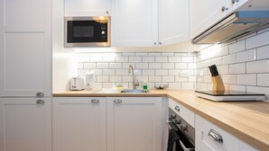 Una cocina moderna con armarios blancos, un microondas, un lavamanos y una encimera de madera.