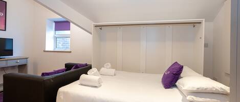 A modern bedroom with a bed, a desk, and a chair.