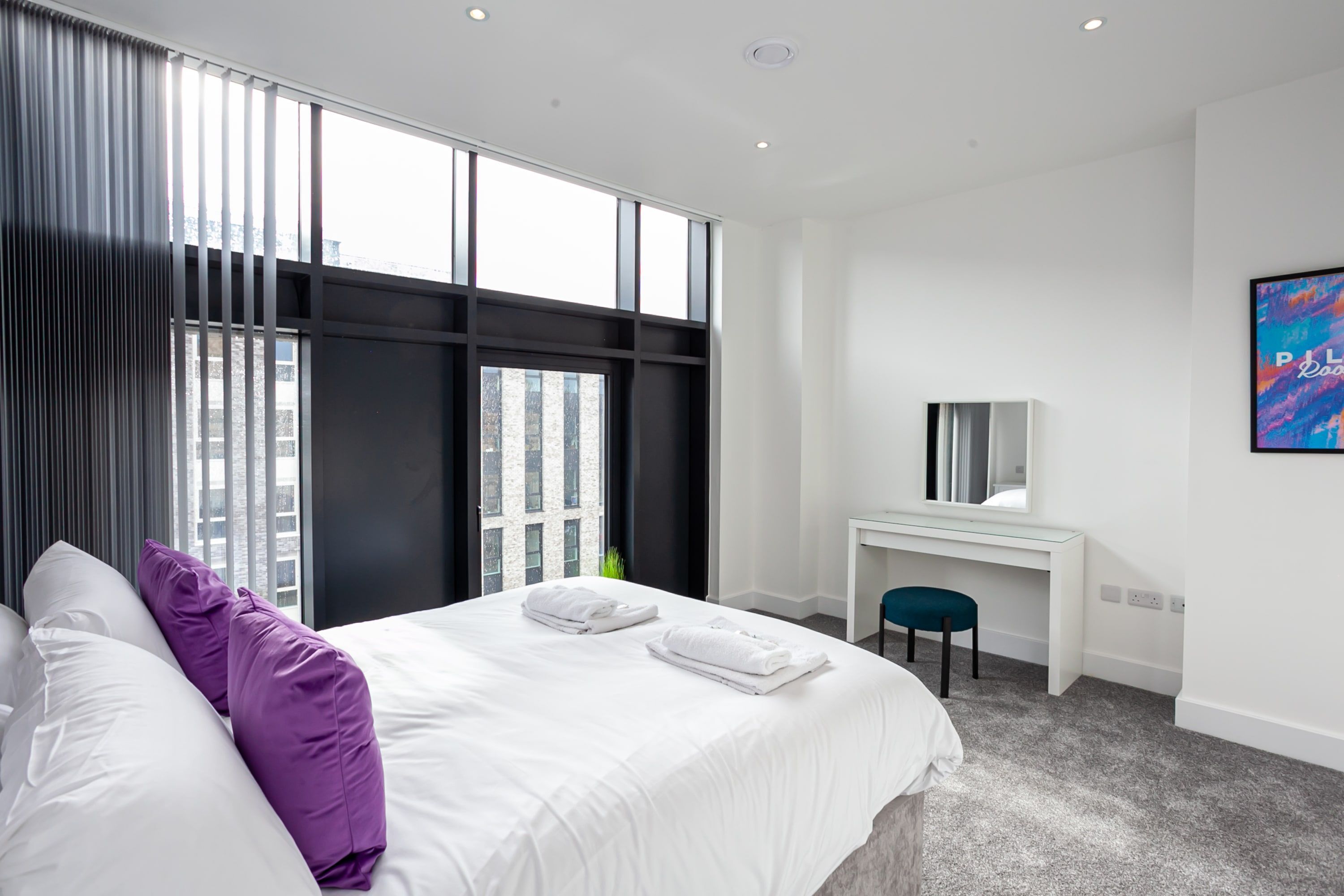 Une chambre d’hôtel moderne, dotée d’un grand lit, d’un bureau et d’une chaise.