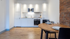 A modern kitchen with white cabinets, a microwave, and a brick wall. - Apartment Close to City Centre and Media City By Pillo Rooms (Salford)