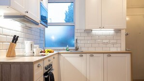 A modern kitchen with white cabinets, a window, and a countertop with kitchen utensils. - Unique 1 Bedroom Apartment by Pillo Rooms (Salford)