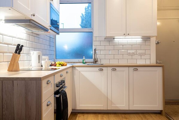 A modern kitchen with white cabinets, a window, and a countertop with kitchen utensils.