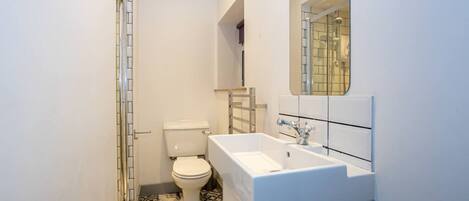 A compact bathroom with a toilet, a white sink, and a mirror above it.