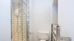 A small, modern bathroom with a glass shower enclosure, a white toilet, and a tiled floor. - Unique 1 Bedroom Apartment by Pillo Rooms (Salford)