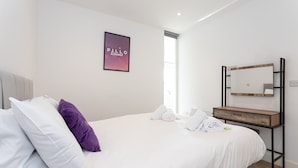 A modern bedroom with a large bed, a bedside table, a mirror, and a framed picture on the wall. - Modern, Stylish 1BR Apartment Nearby AO Arena (Manchester)