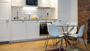 Una cocina moderna con armarios blancos, un microondas y una pared de ladrillo.