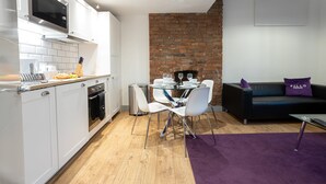 Una cocina moderna con armarios blancos, un microondas y un comedor con una mesa y sillas.