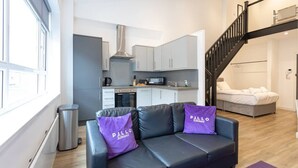 A modern living space with a sofa, a staircase, a kitchen, and a bed. - Modern and Spacious Duplex in Manchester City Centre (Manchester)