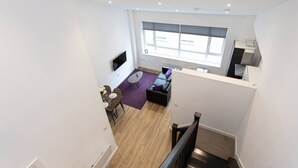 A modern apartment with a dining area, a living room with a sofa and a TV, and a kitchen area. - Modern and Spacious Duplex in Manchester City Centre (Manchester)