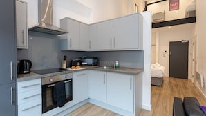 A compact kitchen with grey cabinets, a microwave, a kettle, and a sink. - Modern and Spacious Duplex in Manchester City Centre (Manchester)