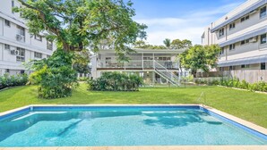 Un edificio residencial con piscina, un área exterior techada y una escalera que lleva a un balcón.