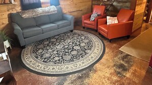 A cozy living room with a grey sofa, a red armchair, and a patterned rug. - Lava Hot Springs Country Cabin (Bancroft)