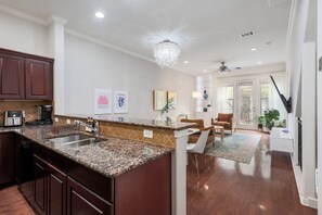 A modern kitchen with granite countertops, a built-in sink, and dark wooden cabinets. - Kinney (Austin)