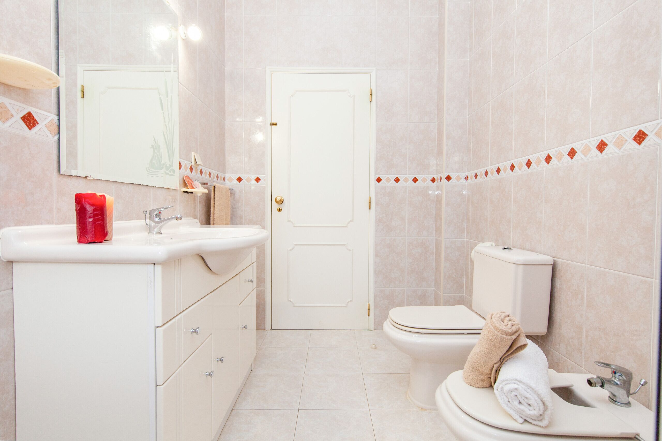 Une salle de bain avec un lavabo blanc, un miroir, des toilettes et un porte-serviettes avec des serviettes.