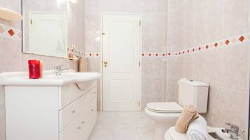 Une salle de bain avec un lavabo blanc, un miroir, des toilettes et un porte-serviettes avec des serviettes.