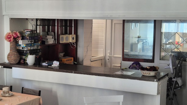 A kitchen with a white countertop, a white door, and a window with a view of the outside. - Glendor Hotel (Blackpool)