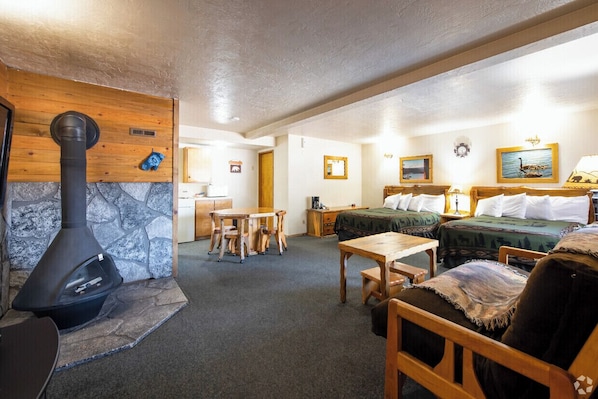 Una habitación acogedora con chimenea de piedra, muebles de madera, una cama con manta verde y un cuadro en la pared.