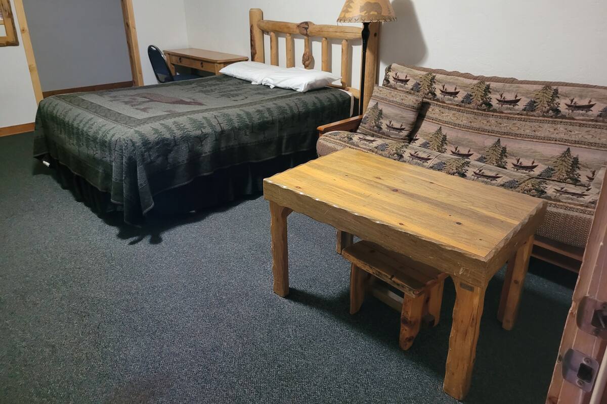 Une pièce comprenant un lit, une table en bois, un canapé et une lampe.