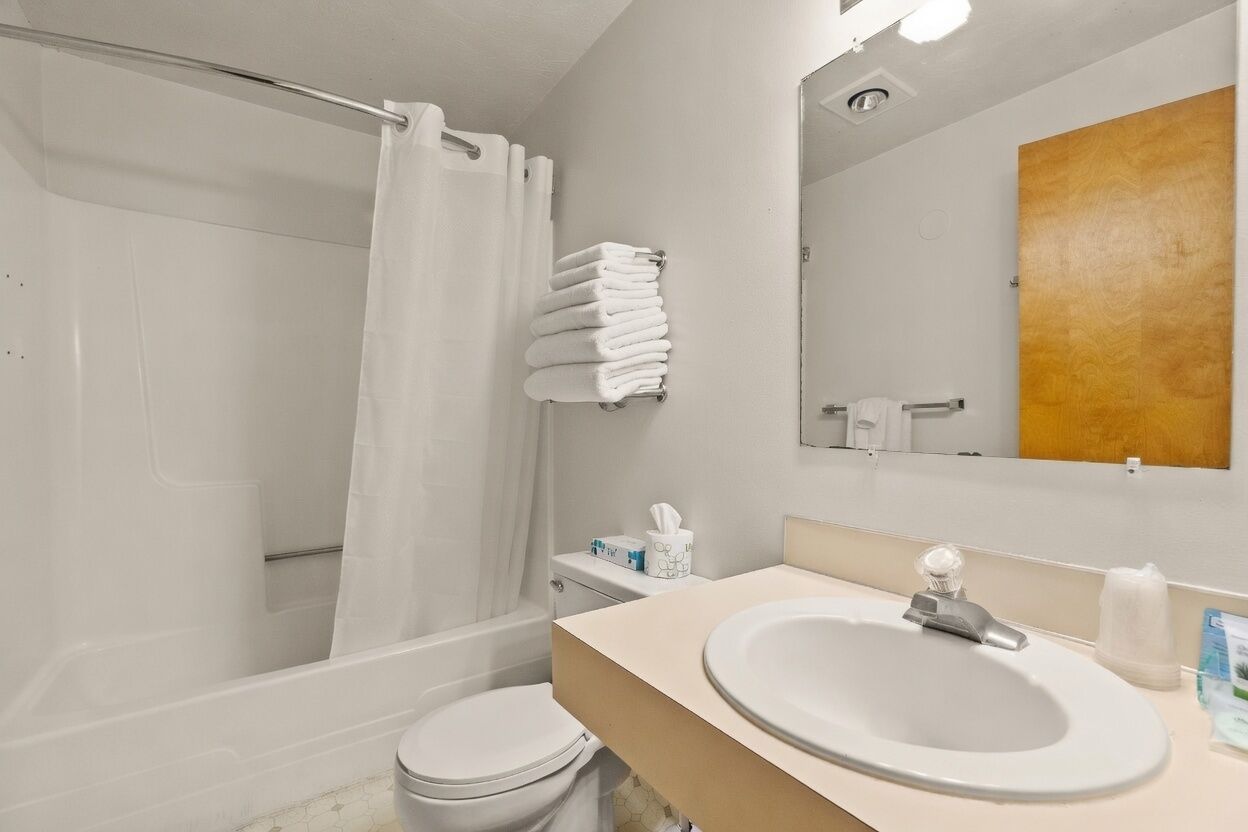 A bathroom with a shower, toilet, sink, and a towel rack.