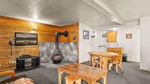 Tunnelmallinen huone, jossa on kivinen takka, puuseinät, ruokapöytä ja keittiötila.