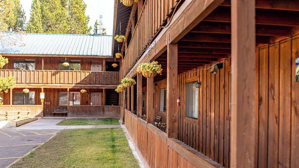Puinen rakennus, jossa on katettu kuisti, roikkuvia kukkaruukkuja ja näkyvillä oleva palosammutin.