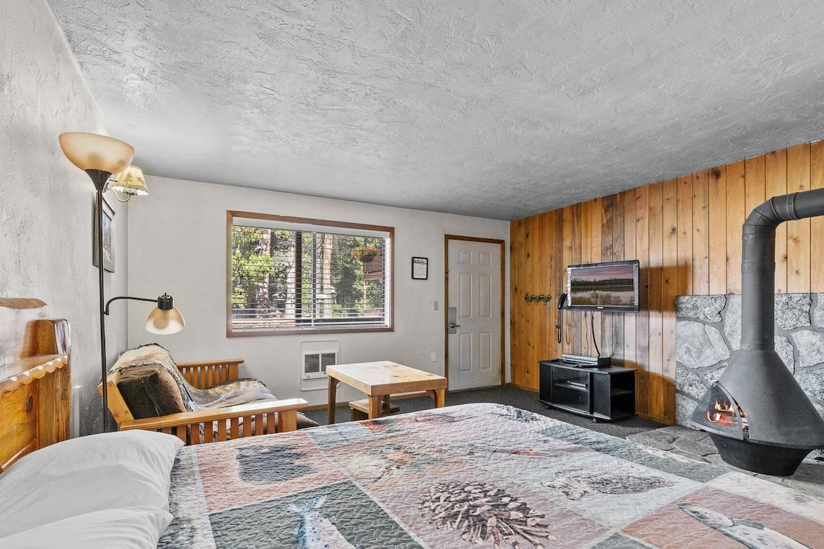 Une pièce confortable avec un lit, un bureau, une chaise, une cheminée et une fenêtre avec des stores.