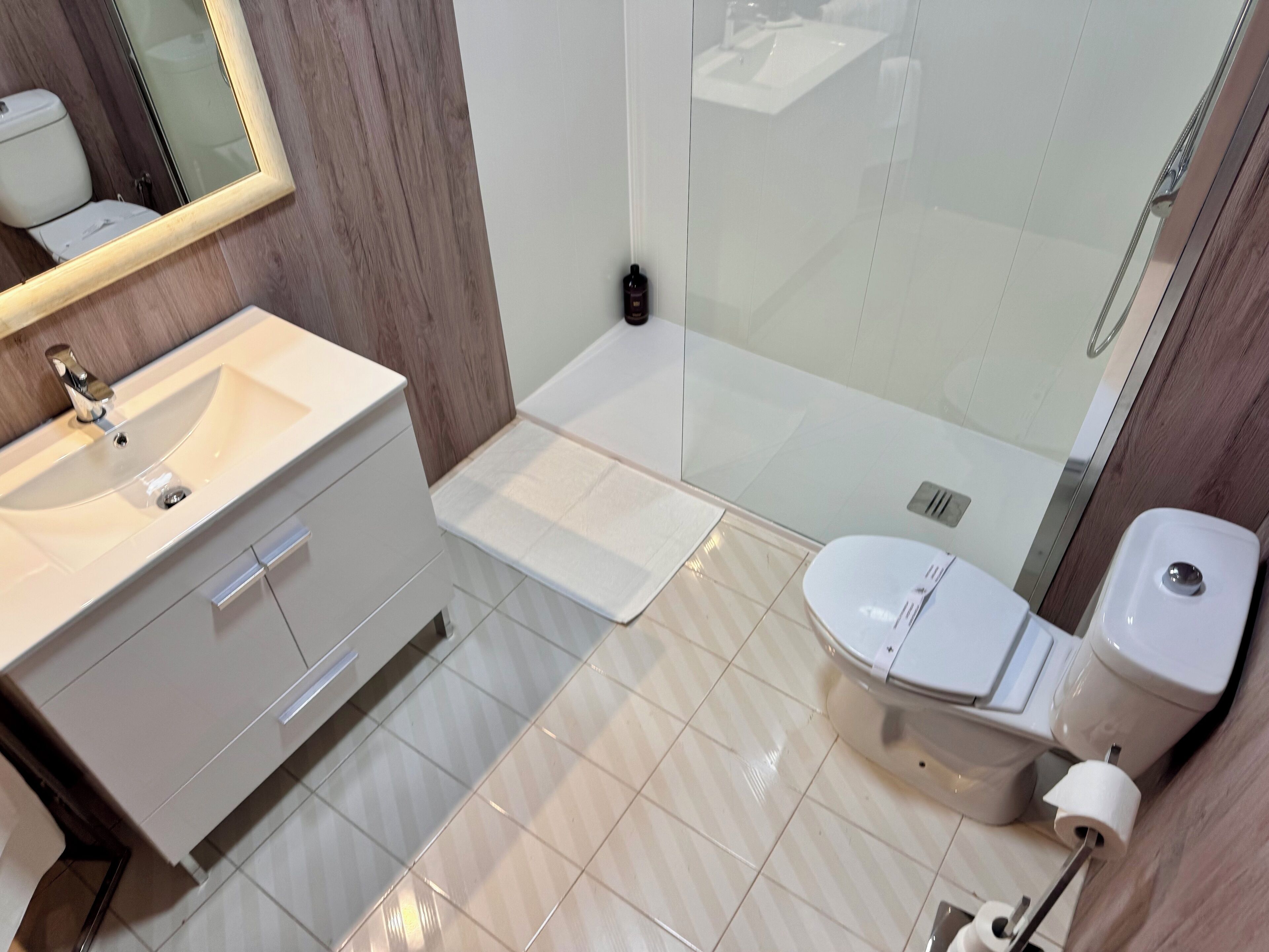 A modern bathroom with a white sink, vanity, and toilet.