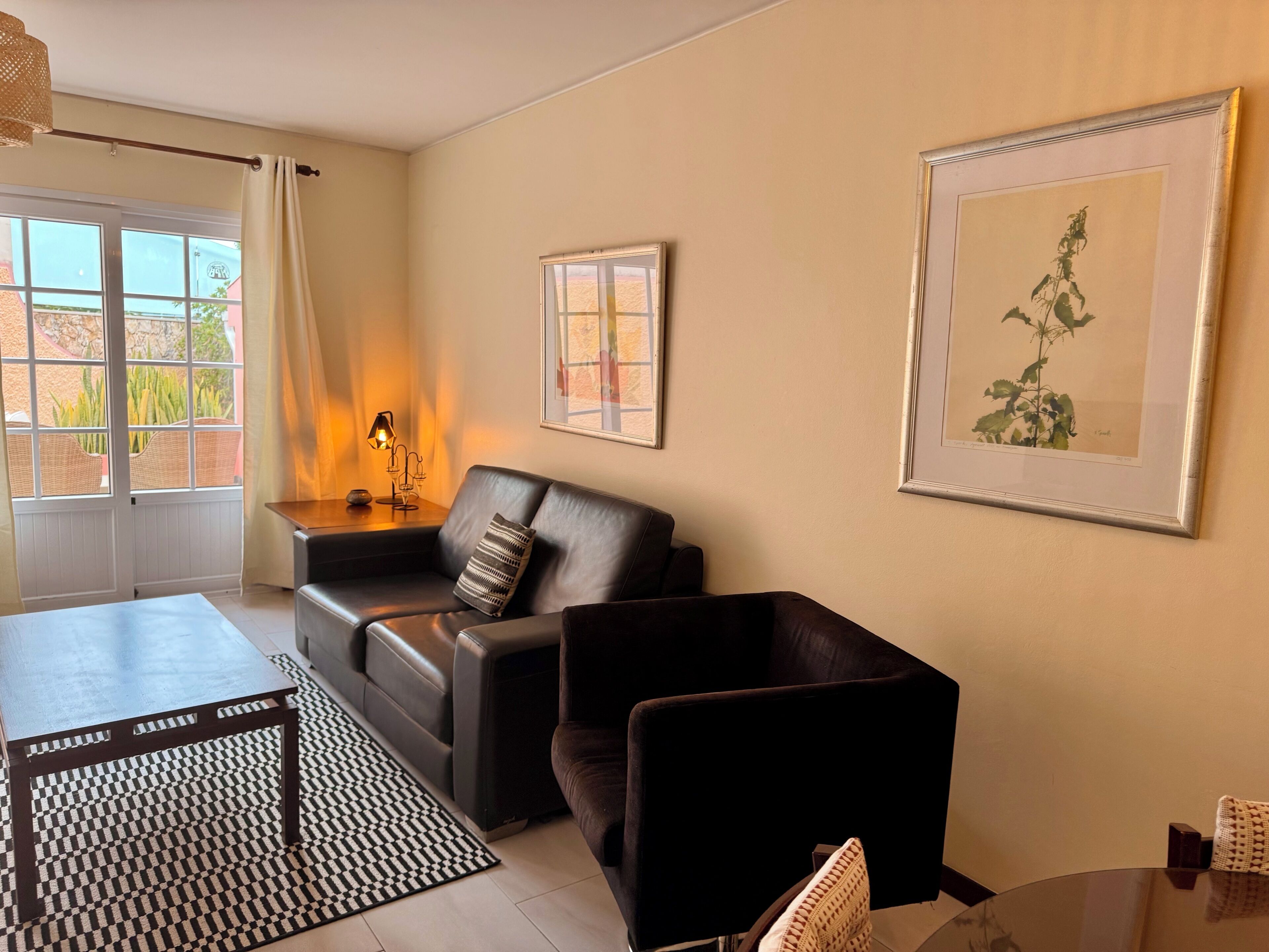 Un salon avec un canapé, une table, une lampe et des œuvres d’art encadrées accrochées au mur.