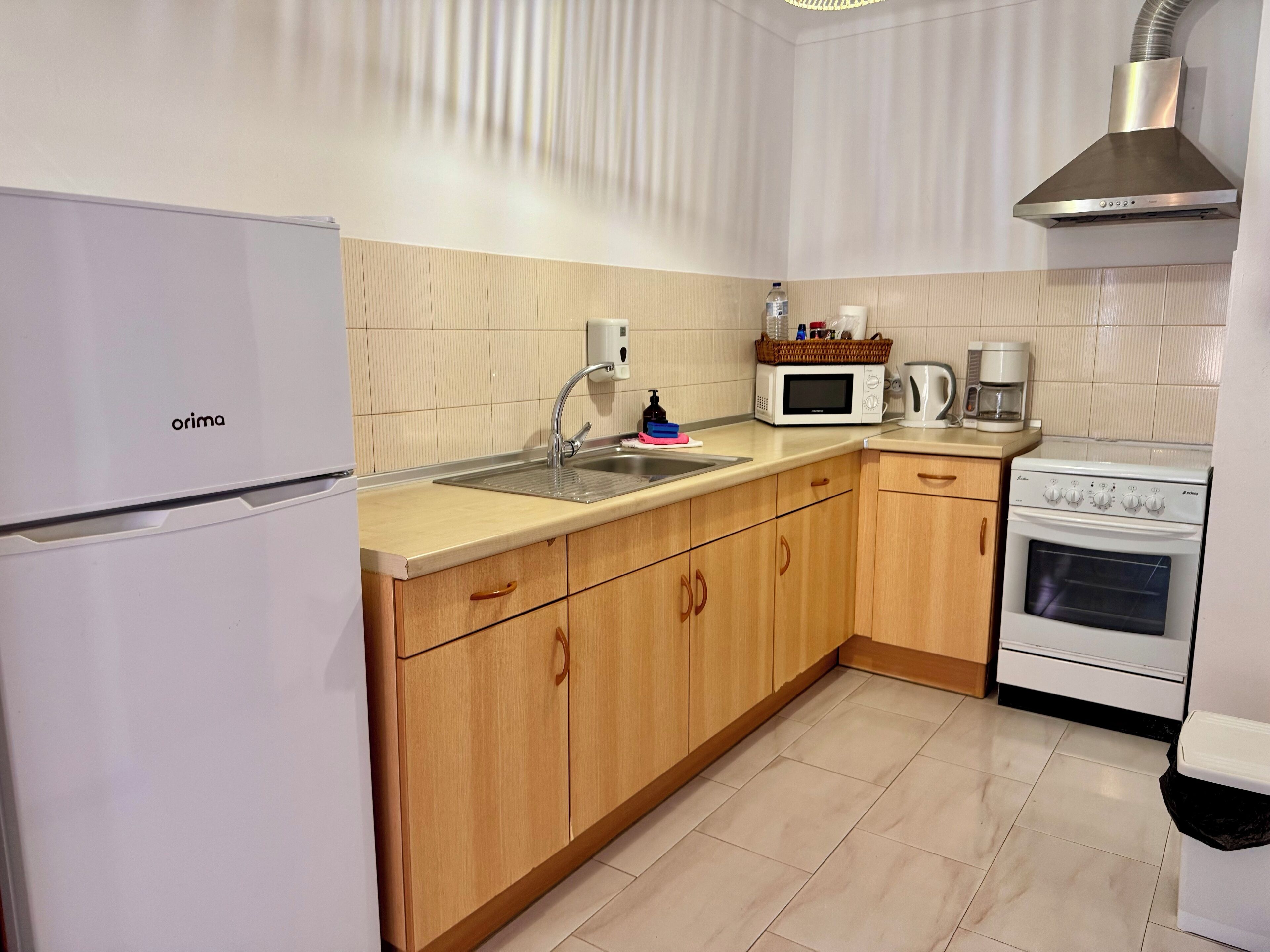 A compact kitchen with a refrigerator, sink, microwave, coffee maker, and stove.