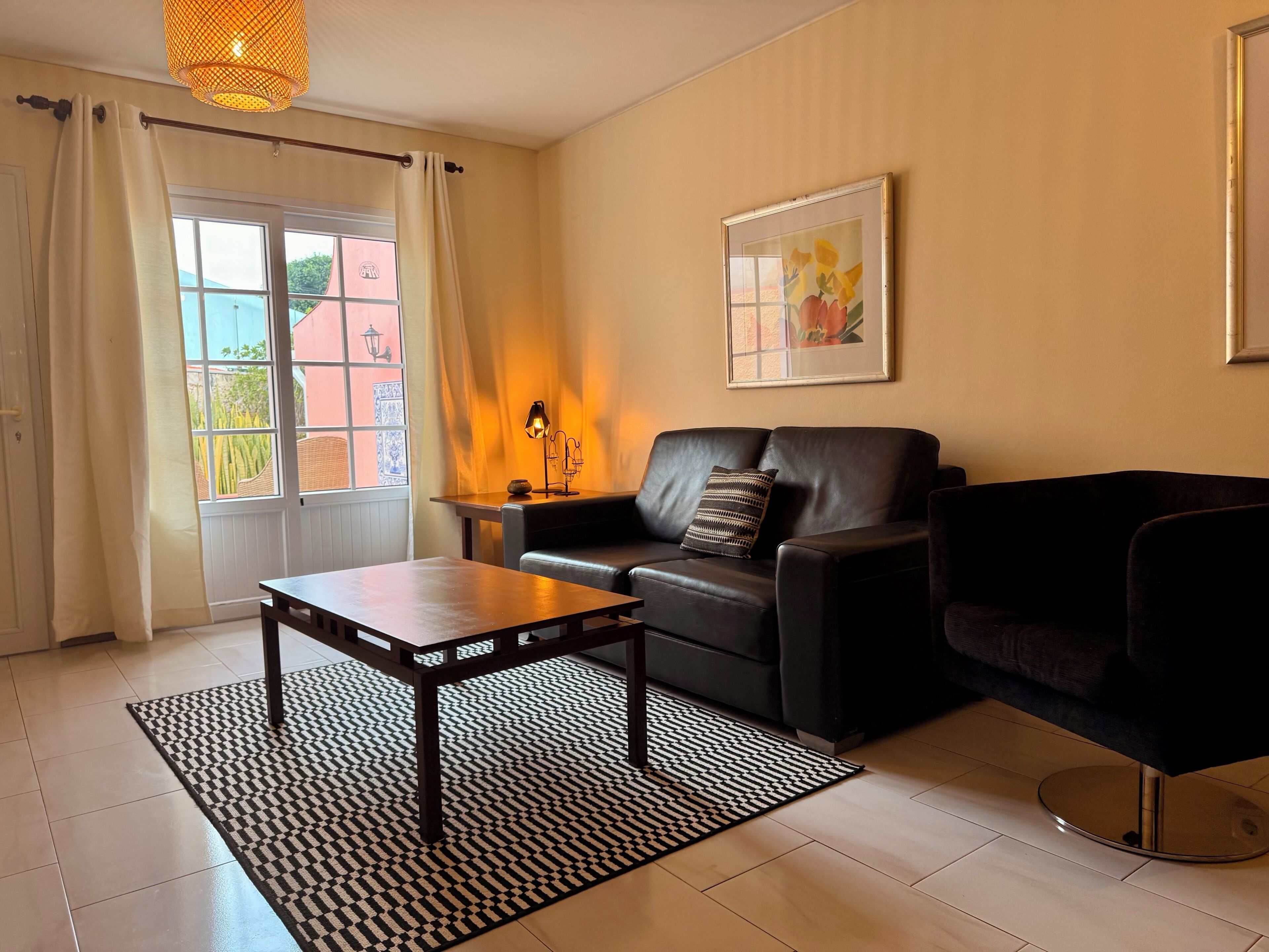 Ett vardagsrum med en soffa, ett soffbord, en lampa och en inramad tavla på väggen.