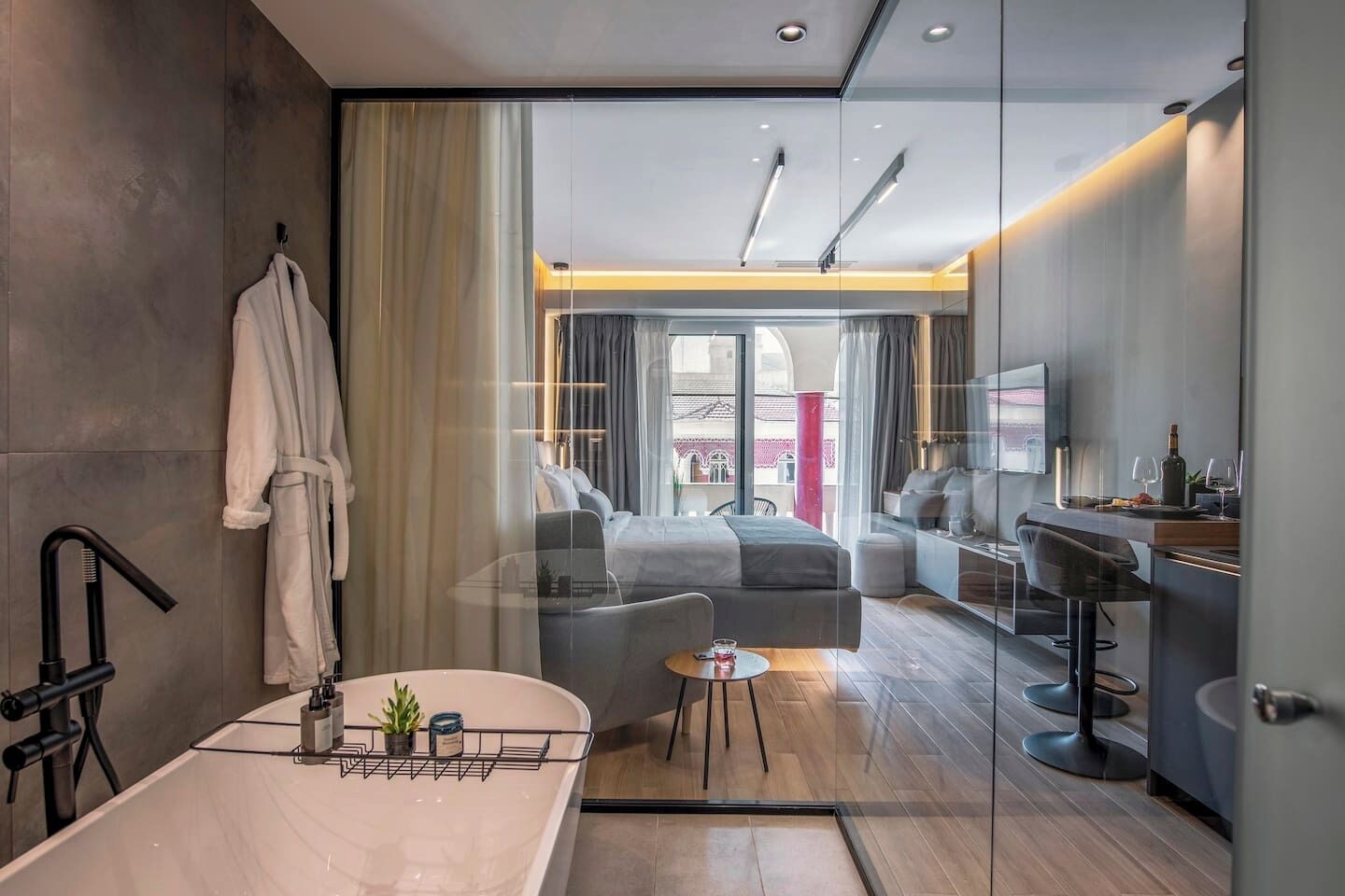 A modern bathroom with a bathtub, a robe hanging, and a glass shower enclosure.