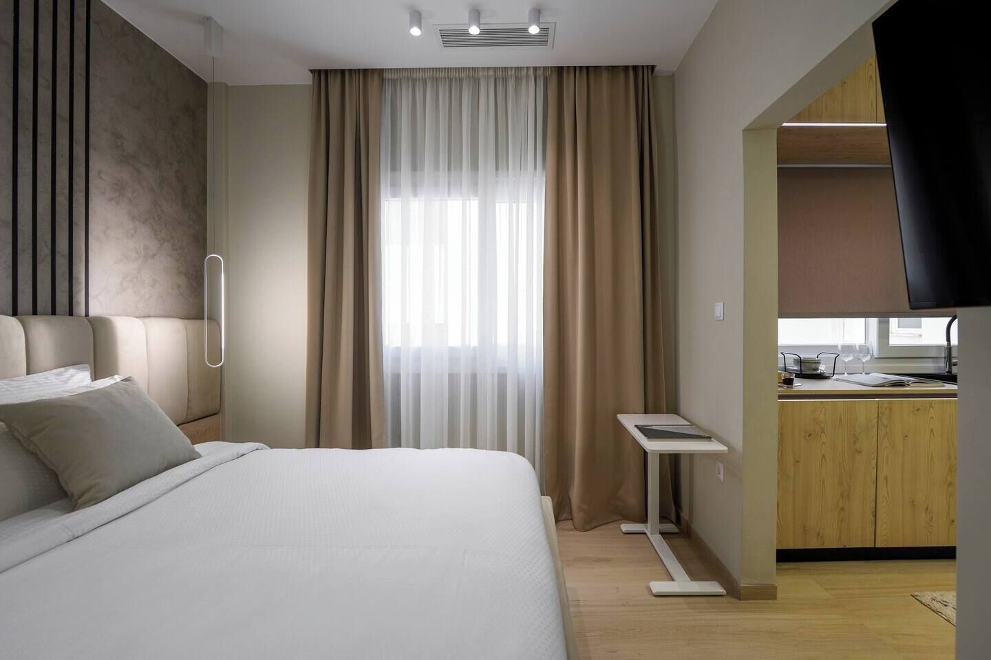 Ein modernes Hotelzimmer mit Bett, Schreibtisch und einer Küchenzeile.